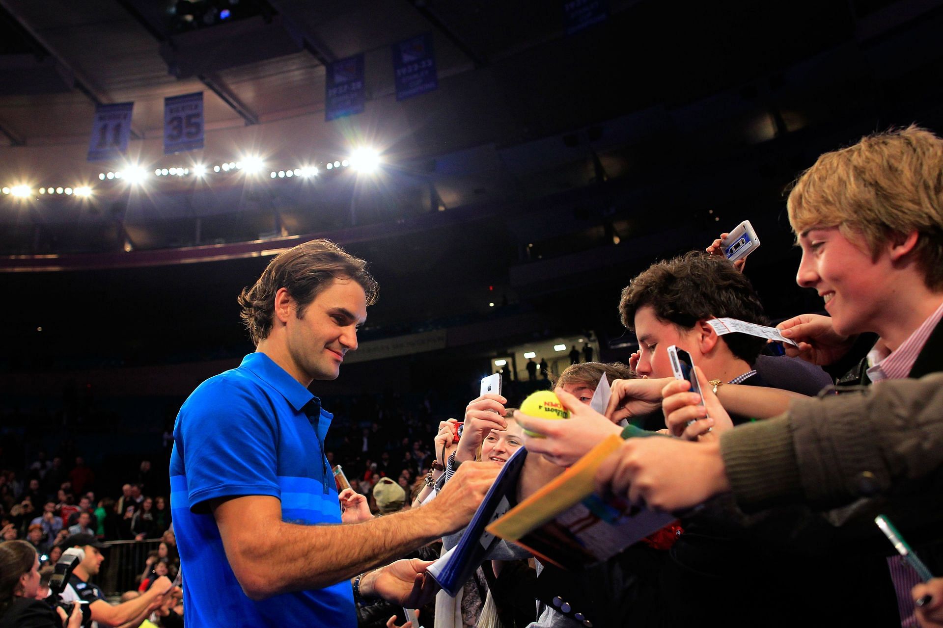 Roger Federer signs autographs following the exhibition match at MSG in 2012